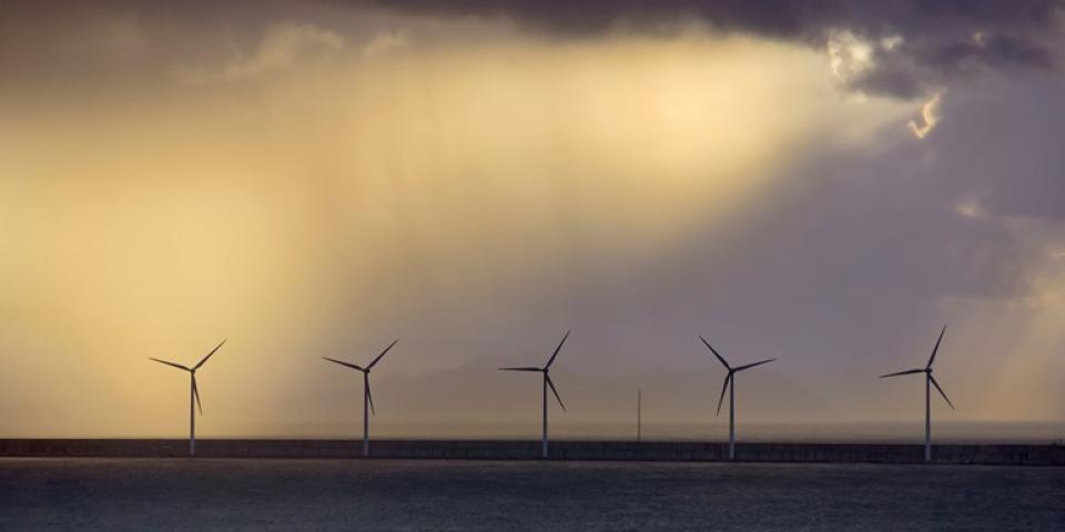 five offshore wind turbines at dusk