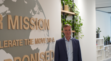 Michael Rea, the Carbon Trust's CEO, in the Carbon Trust office at Arbor in London, next to a mission statement that says "Our mission is to accelerate the move to a decarbonised future"