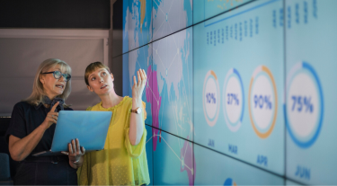 Two women pointing at a  map and data points