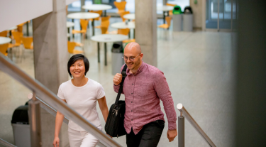 Woman and a man carrying books up stairs