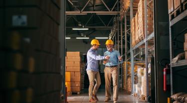Two men wearing hard hats in a warehouse