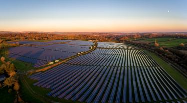 Aerial drone view of solar panels at a solar energy generation farm at Sunset in South Wales, UK