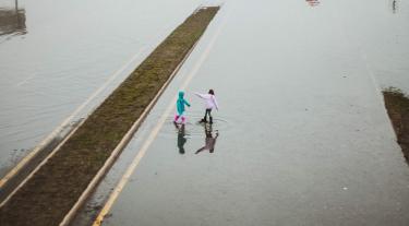 two children play in a flood on a road